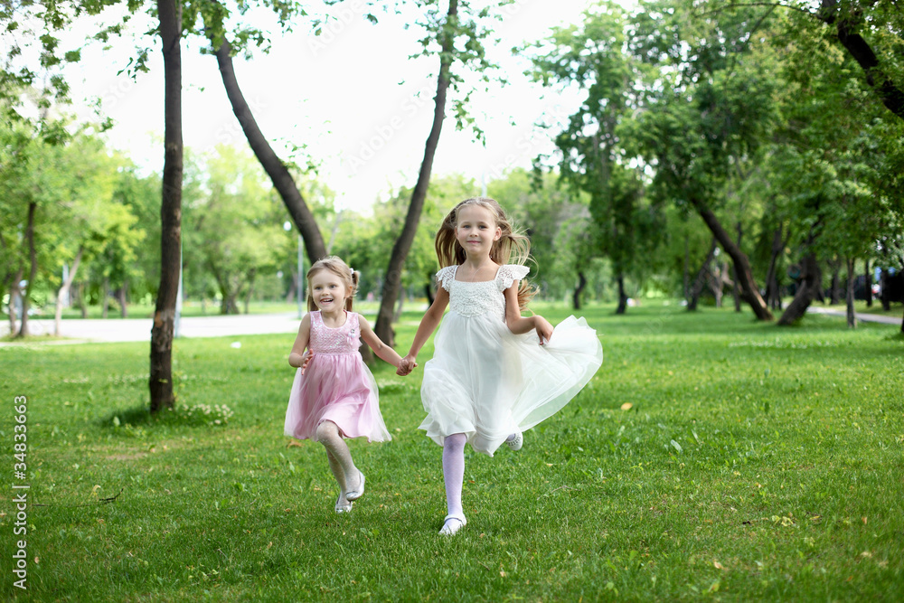 Two little sisters in the summer park Two little sisters in the summer park