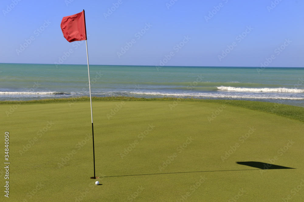 Obraz premium Golf-Grün mit Ball und Fahne am Meer