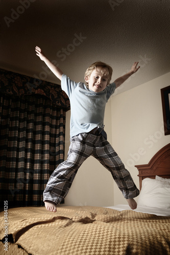 Vászonkép Young boy jumping on the bed