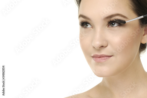pretty young woman applying mascara using lash brush