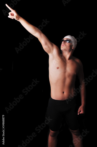 Male swimmer pointing at isolated in black