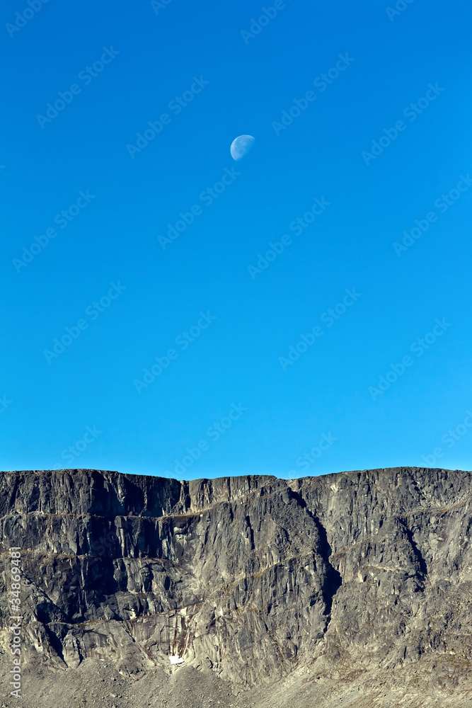 Moon on a background of blue sky and mountains