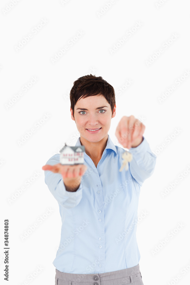 Businesswoman showing keys and a miniature house Businesswoman showing keys and a miniature house