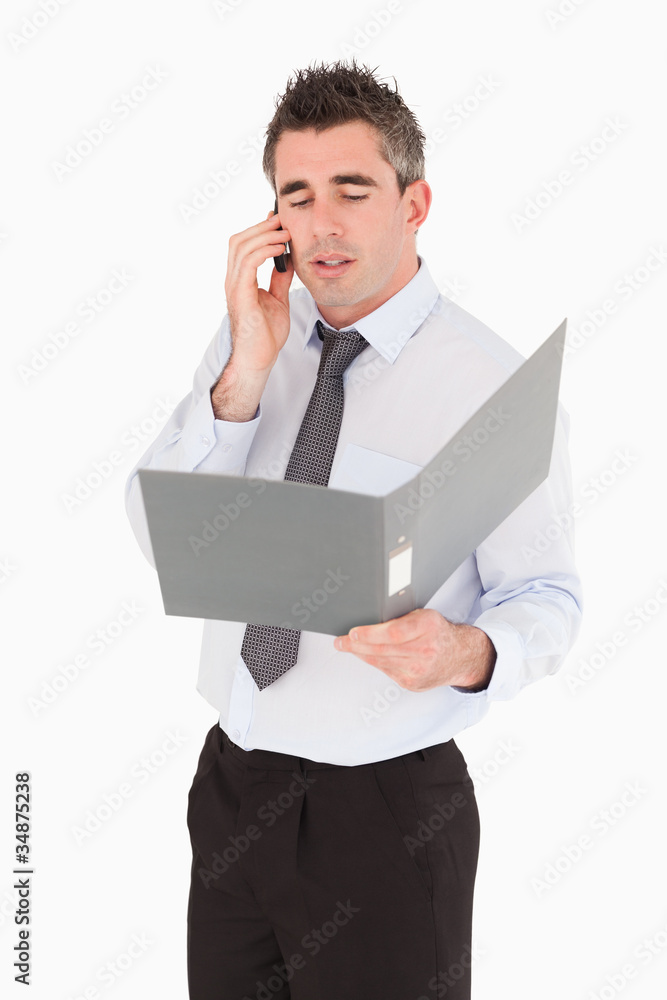 Portrait of a businessman making a phone call while holding a bi Portrait of a businessman making a phone call while holding a bi
