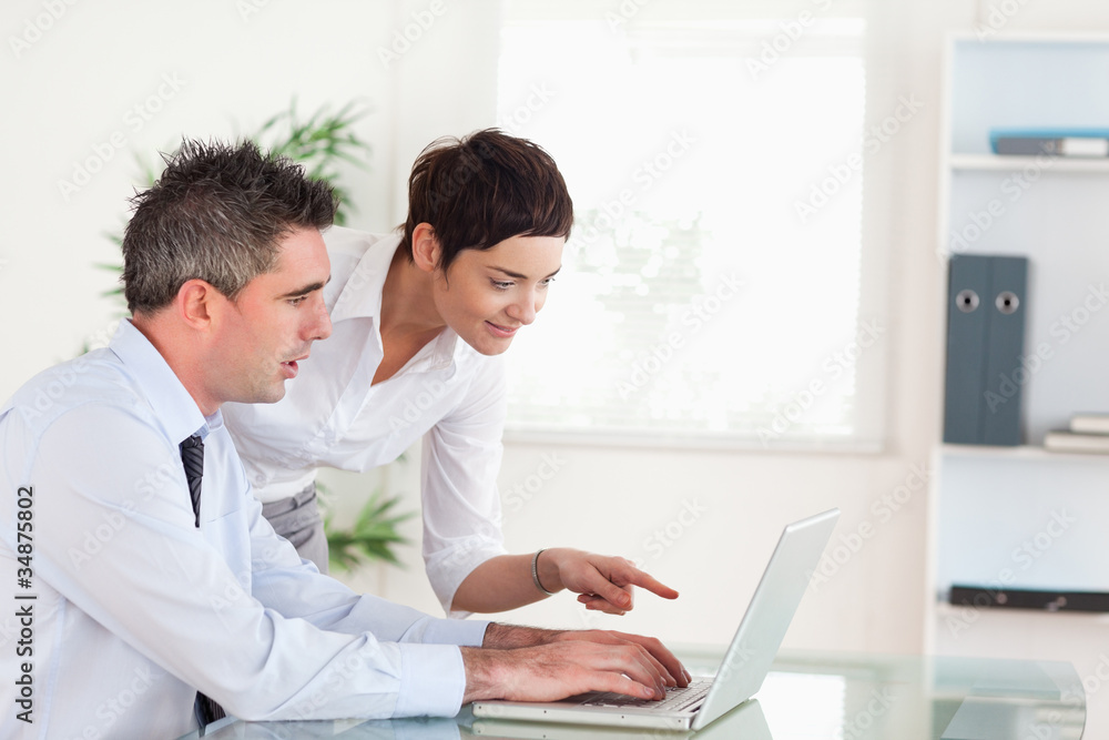 Woman pointing at something to her colleague on a laptop Woman pointing at something to her colleague on a laptop
