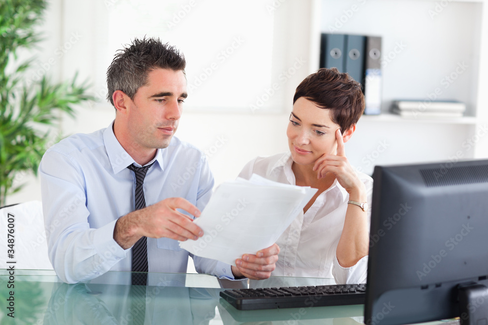 Manager and his secretary reading a blueprint document Manager and his secretary reading a blueprint document