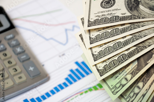 Close-up money against the stock chart and calculator.