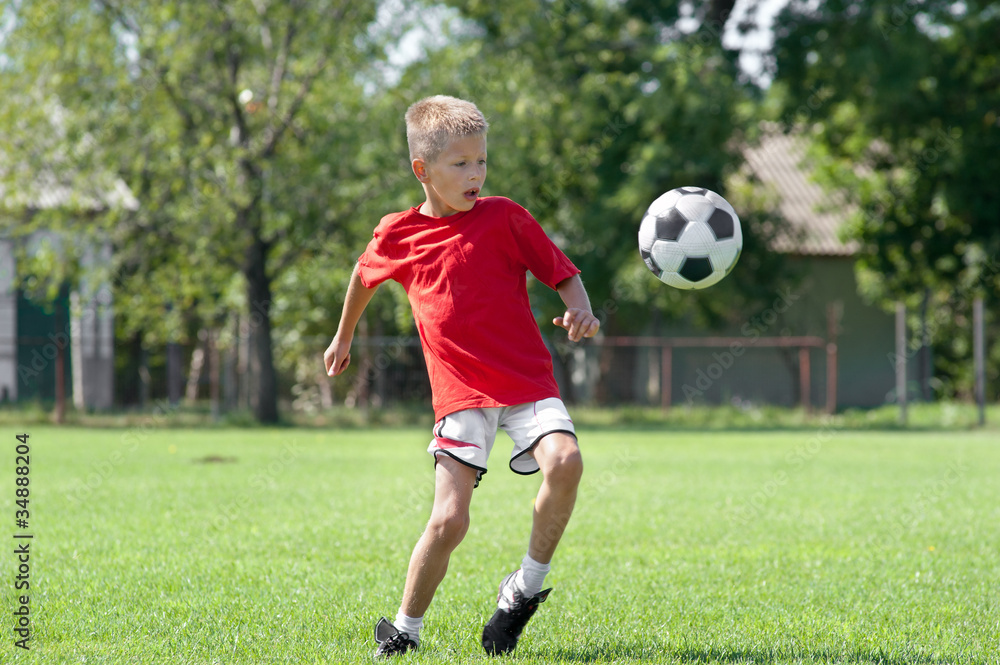 Child playing football on a soccer field