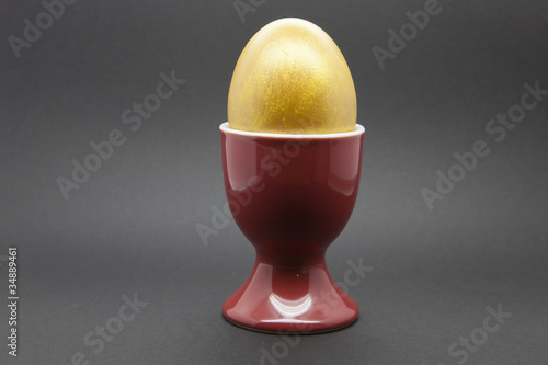 Golden Egg in a red egg cup on a black background