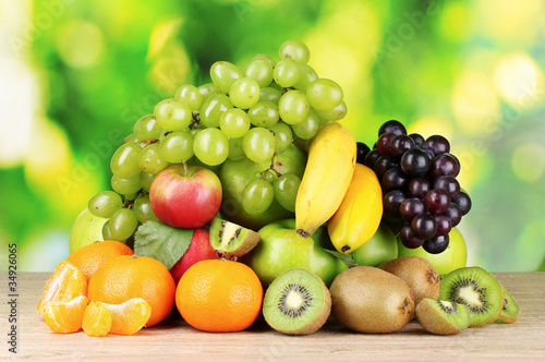 Fototapeta Naklejka Na Ścianę i Meble -  Ripe juicy fruits on wooden table on green background