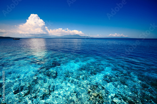 Photos Blue shallow sea with coral reef and fluffy clouds on the horizon