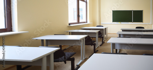 Empty beige classroom with wooden school desks