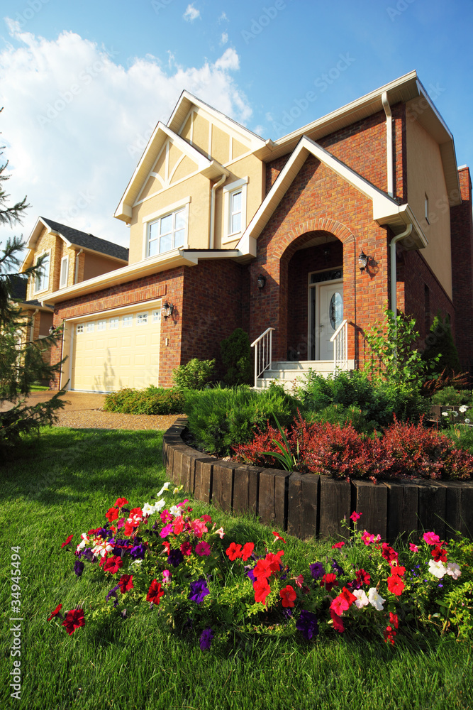 Garden with flowers in front of two-storied brick house