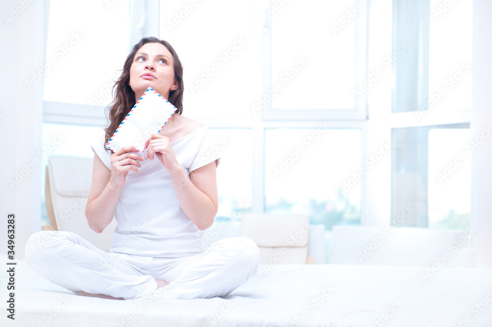 American or european young pretty woman sitting on bed in bright American or european young pretty woman sitting on bed in bright