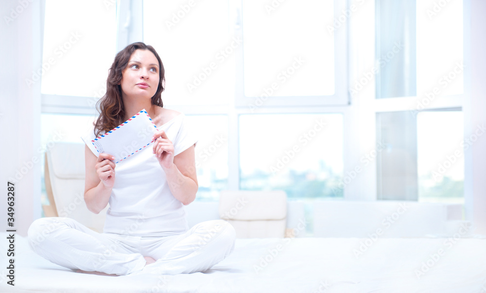 American or european young pretty woman sitting on bed in bright American or european young pretty woman sitting on bed in bright
