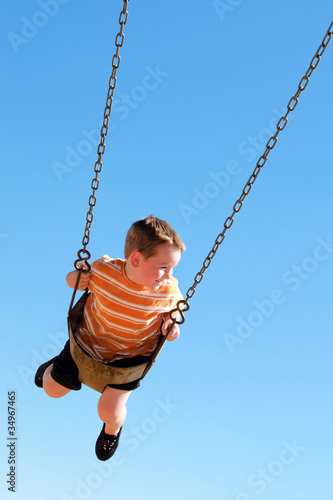 Cute young boy swings at kid park playground