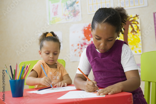 Jeunes enfants en classe de maternelle dessinant photo