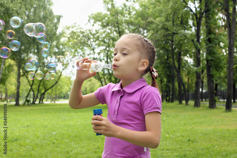Little girl in the park blowing bubbles Little girl in the park blowing bubbles