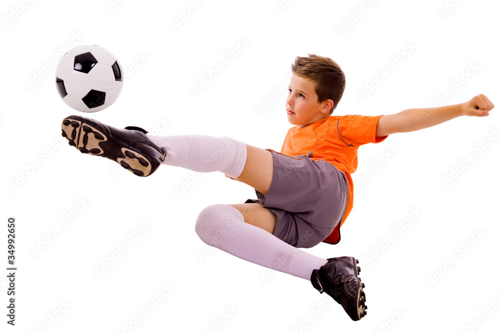 Naklejka premium Young boy with soccer ball doing flying kick, isolated on white