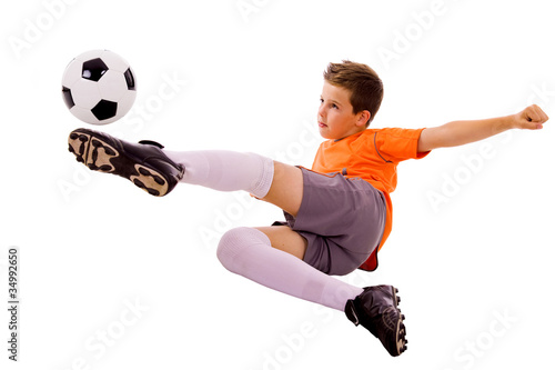 Young boy with soccer ball doing flying kick, isolated on white