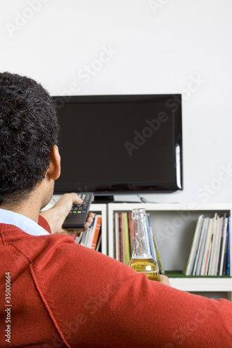 Smart business man drinking beer while watching television