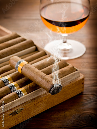smoking cuban cigar and glass of liquor on wood