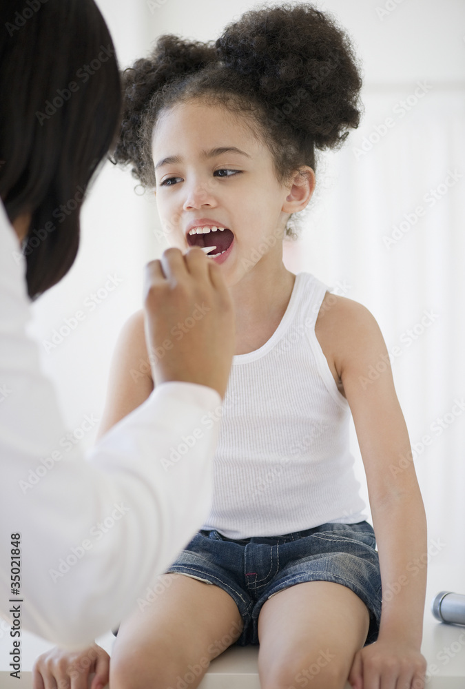 Pediatrician with tongue depressor examining patient Stock Photo