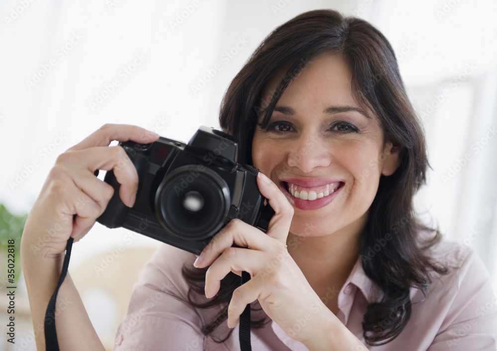 Smiling Hispanic woman holding digital camera Smiling Hispanic woman holding digital camera