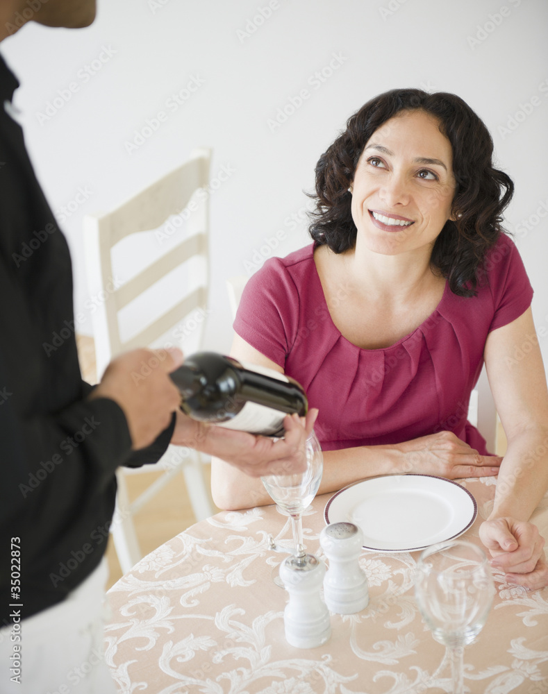 Waiter showing wine bottle to customer at table in restaurant Waiter showing wine bottle to customer at table in restaurant