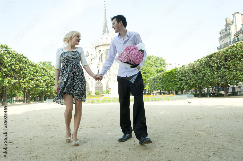 Caucasian couple holding hands in park near Notre Dame Caucasian couple holding hands in park near Notre Dame