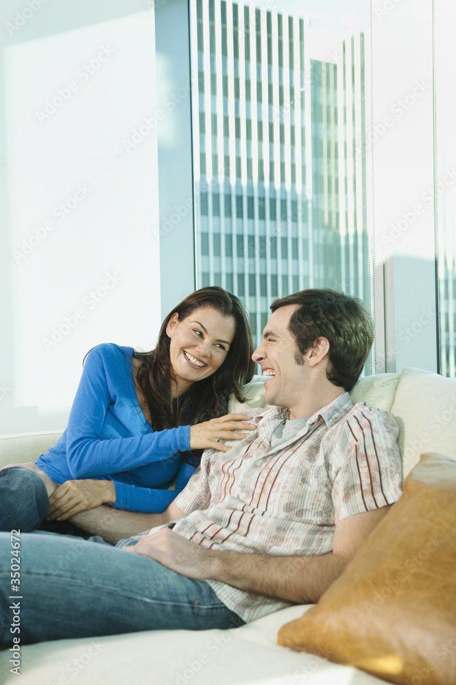 Couple laughing together on sofa Couple laughing together on sofa