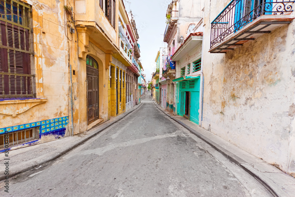 Fototapeta premium Colorful street in Old Havana sidelined with decaying buildings