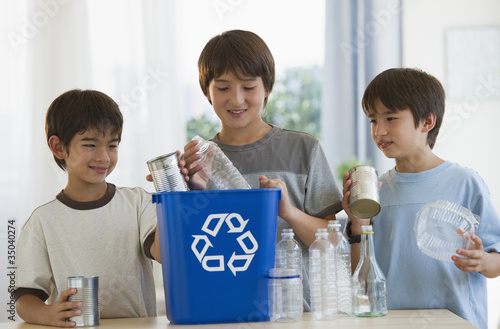 Mixed race brothers recycling plastic bottles and tin cans photo