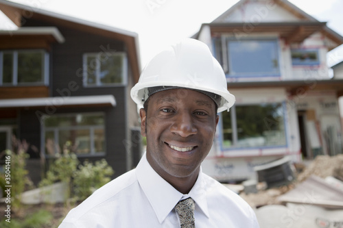 Smiling Black real estate agent in hard-hat near construction site photo