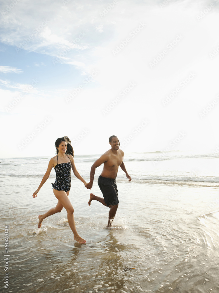 Couple holding hands and running on beach Couple holding hands and running on beach