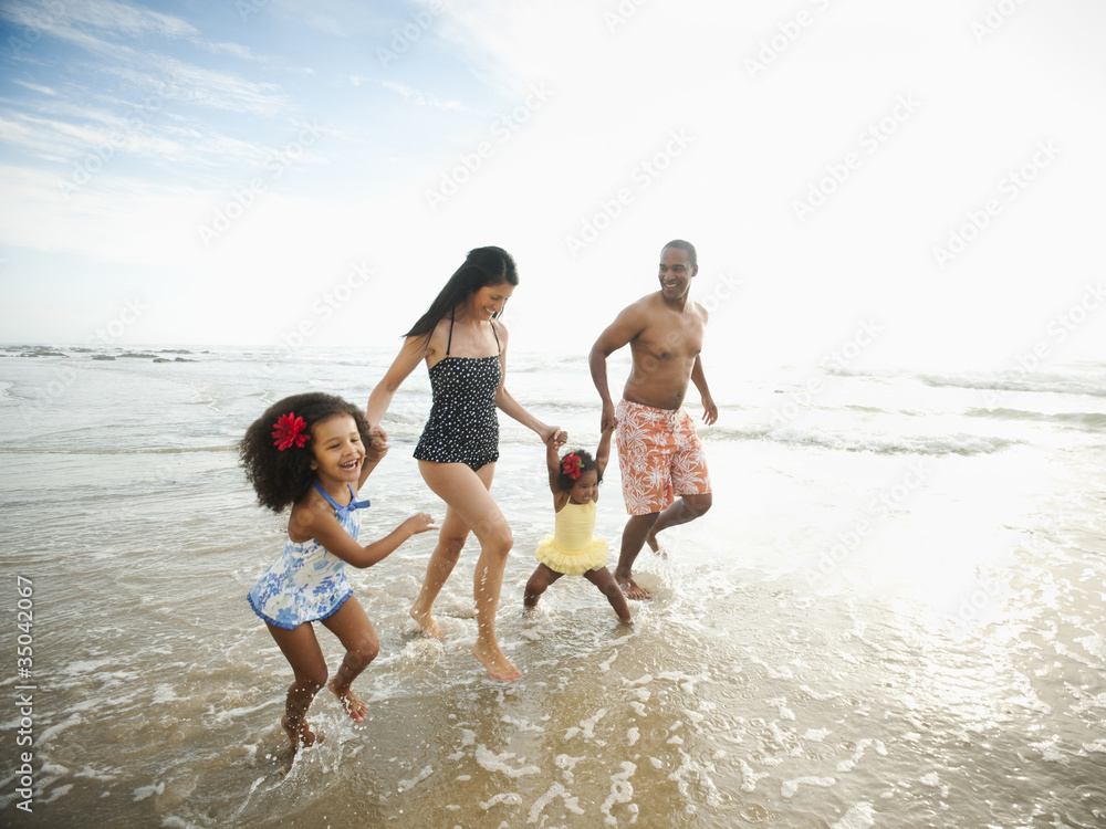 Family holding hands and wading through ocean water