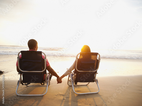 Couple holding hands on beach at sunset photo