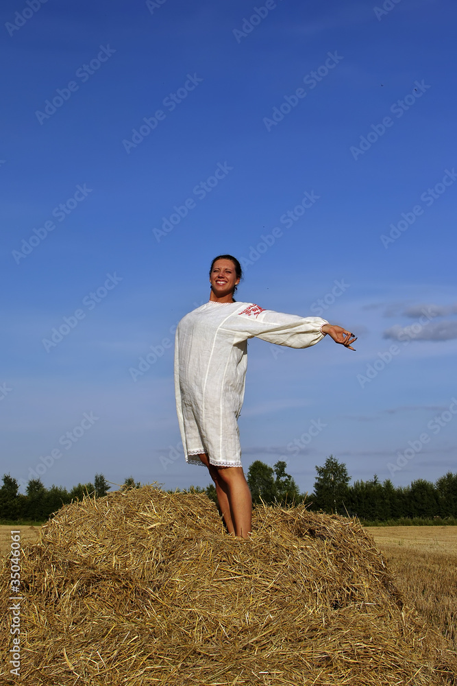 girl in traditional Russian costume standing on a haystack girl in traditional Russian costume standing on a haystack
