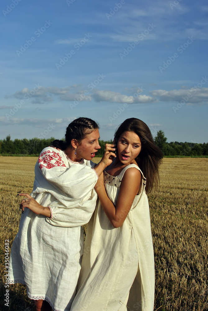 Two girls in a rural clothing talking on the phone Two girls in a rural clothing talking on the phone