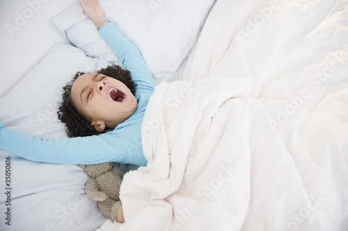 African American girl waking up in bed