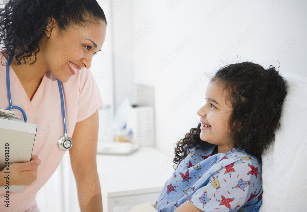 Smiling nurse talking to girl in hospital bed Smiling nurse talking to girl in hospital bed