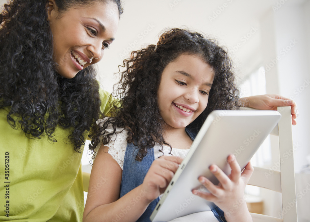 Mother and daughter using digital tablet together Mother and daughter using digital tablet together