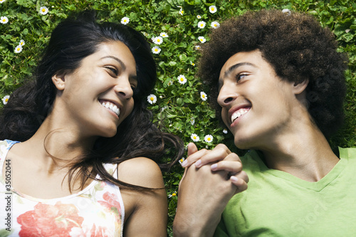 Teenage couple laying in grass holding hands photo