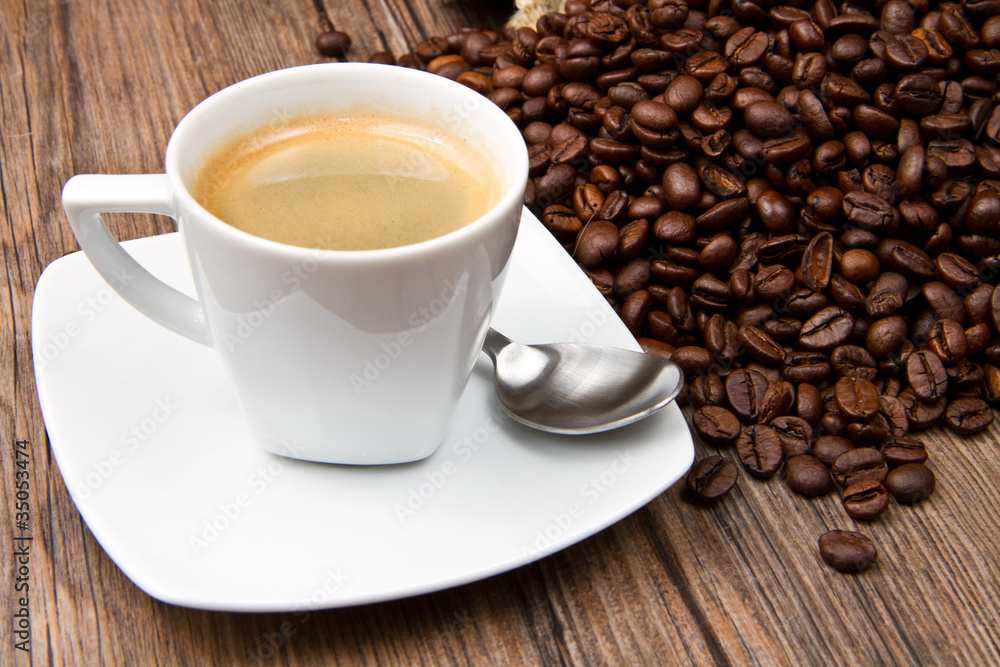 Fototapeta premium Coffee cup with roasted beans on rustic table