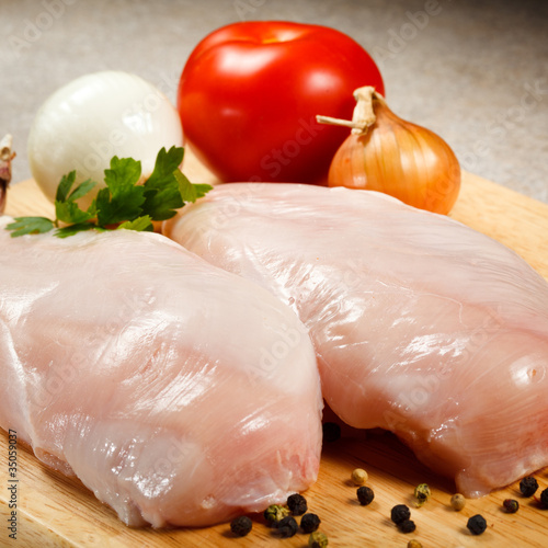 Raw chicken breasts on cutting board
