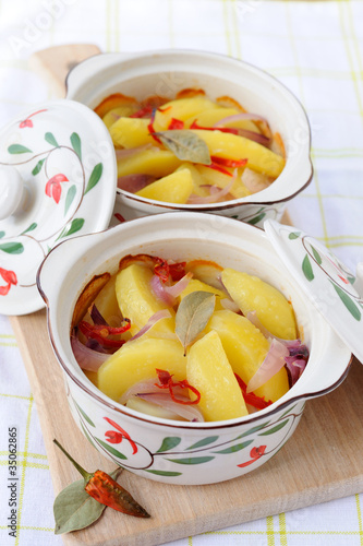 Two pots with baked potato with hot pepper and onion