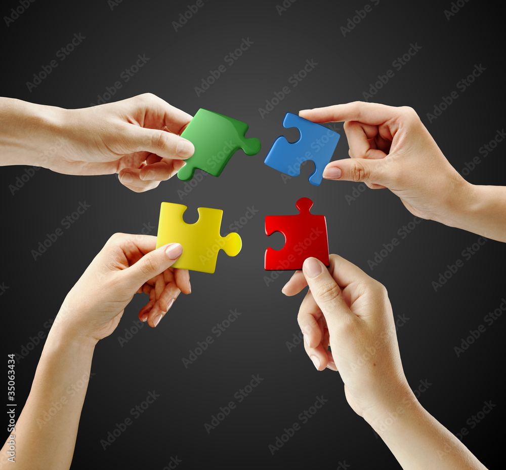Hands and puzzle on black background. Teamwork solving a puzzle Hands and puzzle on black background. Teamwork solving a puzzle