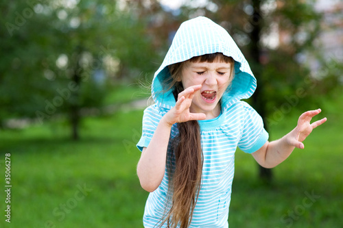 Cute child girl poses outdoors with scary face