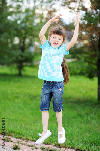 Happy child girl is jumping in the air outdoors