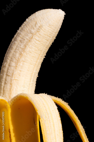Canvastavla A half pealed banana close up with a black background